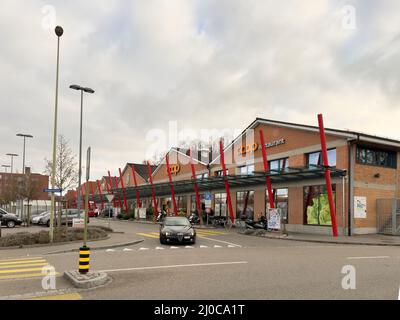 Basilea, Svizzera - 20 dicembre 2021: Ristorante Coop nel centro di Basilea con una macchina Alfa Rome che guida sulla strada quasi vuota Foto Stock