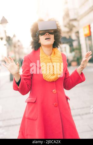 Ritratto di giovane bella donna utilizzando occhiali di realtà virtuale high-tech all'aperto Foto Stock
