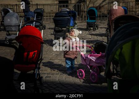 Lviv, Ucraina. 18th Mar 2022. Emilia, 2, di Kyiv si esibir in "Price of Freedom" in Piazza Rynok a Lviv, Ucraina il 18 marzo 2022. La famiglia EmiliaÃs fuggì da Kiev due settimane fa. I passeggini, che rappresentano gli almeno 109 bambini uccisi dall'invasione russa del 24 febbraio, sono destinati a sensibilizzare UkraineÃs al desiderio di avere il paese una zona senza volo. Credit: ZUMA Press, Inc./Alamy Live News Foto Stock
