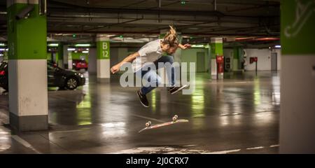 Skater fare trucchi e saltare nel garage sotterraneo. Pattinaggio urbano gratuito Foto Stock