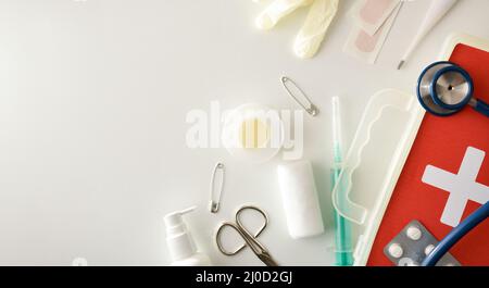 Apparecchiatura portatile di pronto soccorso di base isolata su un lato del tavolo bianco. Composizione orizzontale panoramica. Vista dall'alto. Foto Stock