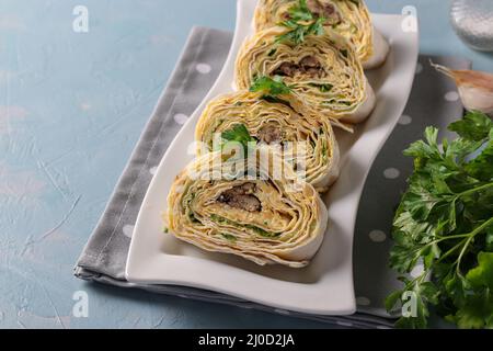 Rotolo di lavasch con spratti, formaggio cremoso, cetriolo e uova su sfondo azzurro. Primo piano Foto Stock