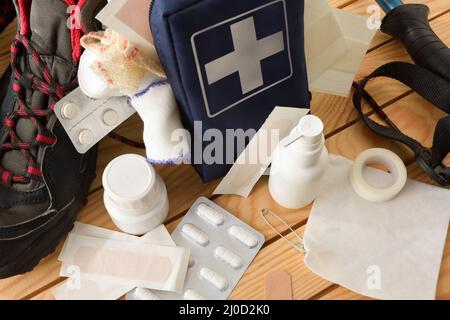 Attrezzatura di pronto soccorso portatile di base per eventi sportivi di natura di svago su tavola di legno e sfondo di alberi. Composizione orizzontale. Vista rialzata. Foto Stock