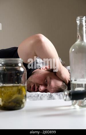 Un uomo ubriaco si trova a letto, tenendogli le mani in testa. Hangover, delirio alcolico. Foto Stock