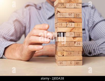 Blocchi di legno torre in uomo d'affari primo piano. Concetto di gestione del rischio finanziario e pianificazione strategica. Foto di alta qualità Foto Stock