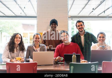 Sorridenti colleghi multietnici che guardano la macchina fotografica facendo foto di squadra in un ufficio moderno insieme - felice gruppo di lavoro diversificato o reparto ridere in posa per fo Foto Stock