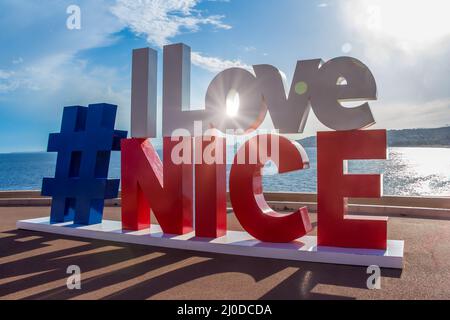 Cartello Hashtag i Love Nice con vista sulla Promenade des Anglais, il luogo turistico più famoso. Famoso sunburst giganti lettere selfie punto al tramonto in Foto Stock