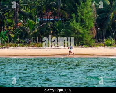 Sindhudurg, India - 20 dicembre 2021 : uomo non identificato con zaino che fa una passeggiata mattutina sul lato della spiaggia Foto Stock