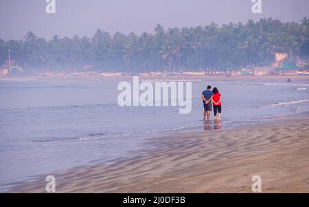 Sindhudurg, India - 20 dicembre 2021: Coppia non identificata che prende una passeggiata mattutina sul lato della spiaggia Foto Stock