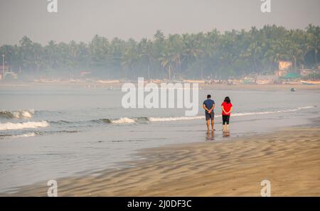 Sindhudurg, India - 20 dicembre 2021: Coppia non identificata che prende una passeggiata mattutina sul lato della spiaggia Foto Stock