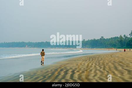 Sindhudurg, India - 20 dicembre 2021 : Coppia non identificata che fa jogging sulla spiaggia durante le ore del mattino. Bella texture di sabbia di mare. Foto Stock