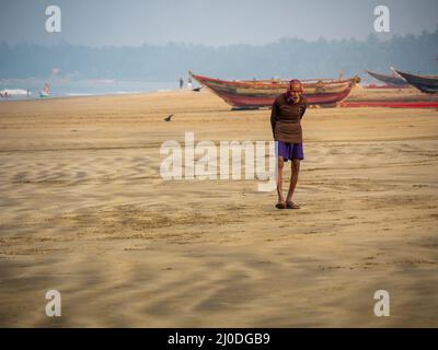 Sindhudurg, India - 20 dicembre 2021 : uomo anziano o anziano non identificato che parla una passeggiata mattutina sul lato della spiaggia Foto Stock