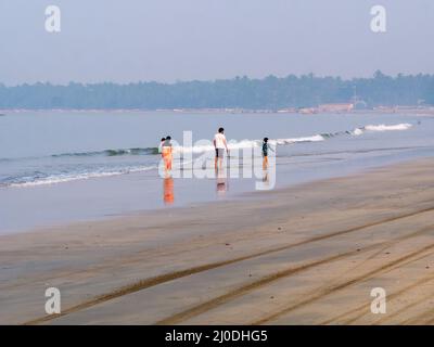 Sindhudurg, India - 20 dicembre 2021 : Famiglia indiana non identificata che sta facendo una passeggiata mattutina sul lato della spiaggia Foto Stock