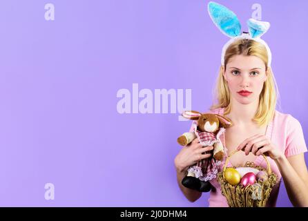 Giorno di Pasqua. Ragazza in orecchie di coniglio con uova cesta e giocattolo coniglietto. Caccia alle uova. Vendita stagionale. Sconto. Foto Stock