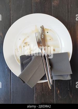 Piatto sporco con forchetta e coltello su tavola di legno dopo cena Foto Stock