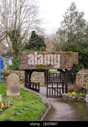 Una porta a doppio lico fuori dalla chiesa di St Giles nel villaggio del Derbyshire di Great Longstone. I tetti delle tegole sono ricoperti di muschio e aiuole di fiori li Foto Stock