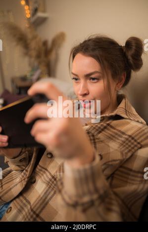 Primo piano. Bella giovane donna con un tablet in mano. Espressione facciale mirata. Videogiochi, freelance, shopping, vendite, tempo libero, hobby. tè Foto Stock