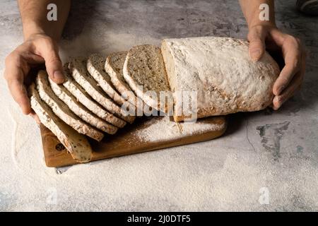 Le mani maschili spalmano il burro su una fetta di pane. Foto di alta qualità. Concetto di cibo sano. Foto Stock