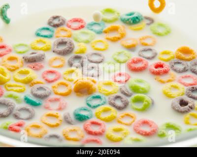 Prima colazione nutriente veloce - frutta colorata anelli di grano intero nel latte. Cibo per bambini, dieta, fitness. Cibo dolce. Vitamine, minerali, fibre. Supermercato, adv Foto Stock