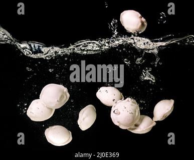 Gnocchi (ravioli) sott'acqua in acqua bollente sott'acqua in padella su sfondo scuro. Cucina italiana, cinese Foto Stock