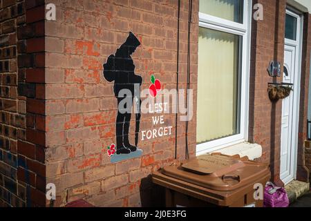 17.03.2022 Sutton, St Helens, Merseyside, Regno Unito. Murial di un soldato e slogan dicendo meno ci dimentichiamo su un muro di mattoni rossi Foto Stock