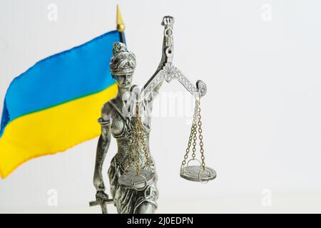 Statua di Themis - Dea di Giustizia e bandiera Ucraina su sfondo bianco. Sistema giudiziario, Costituzione, Stato di diritto, protezione dell'Ucraina fra Foto Stock