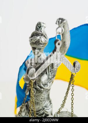 Primo piano - una statua della dea della giustizia - Themis sullo sfondo della bandiera Ucraina. Lo Stato di diritto, il processo della Russia, che scatena Foto Stock