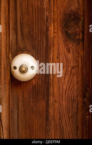 Pulsante campanello rustico in stile tradizionale vecchio stile su una porta di legno Foto Stock