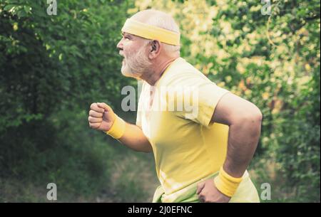 Corridore senior in natura. Allenamento cardio. In funzione nel parco la mattina. Il maschio anziano sta godendo lo stile di vita sportivo. Concetto di stile di vita sano Foto Stock