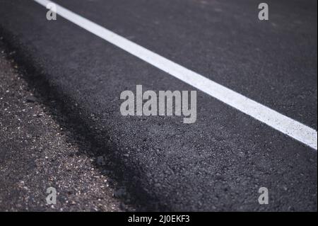 particolare di una linea bianca dipinta sul lato di una strada asfaltata in costruzione Foto Stock