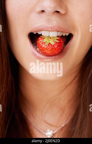 Frutta deliziosa. Immagine ritagliata di una donna con una fragola in bocca. Foto Stock