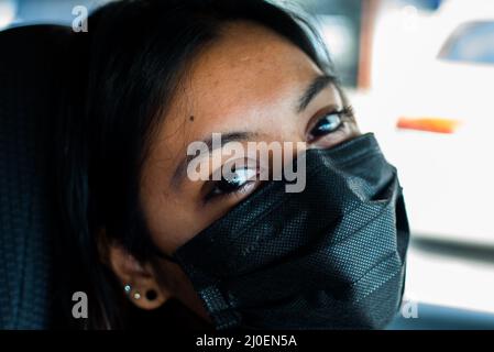 Donna sorridente dietro Mask Foto Stock