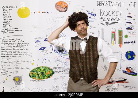 Scienziato caucasico di mezza età di razzo in piedi di fronte ai disegni astronomici sul reparto di parete di Foto Stock