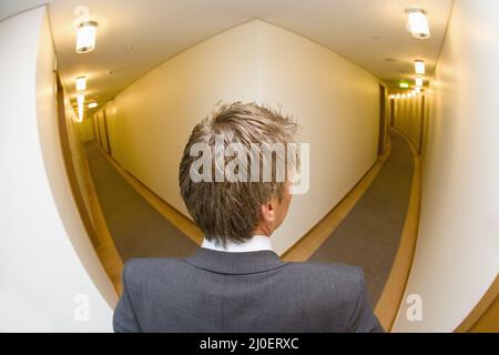 Un uomo d'affari che guarda lungo la porta d'ingresso di un hotel girato dall'alto Foto Stock