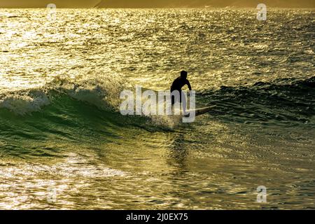 Surfista sulle onde della spiaggia di Ipanema al tramonto Foto Stock