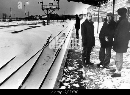 I lavoratori della mattina presto aspettano alla stazione di Barry un treno. La pista da Barry alla Island Station è stata bloccata dalla neve sulla pista, che si può vedere a sinistra della foto, Barry stazione ferroviaria, vale di Glamorgan nel Galles del Sud, 21st febbraio 1978. Foto Stock