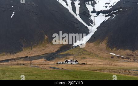 Tipico paesaggio islandese con case coloniche coperte di neve in Islanda Foto Stock