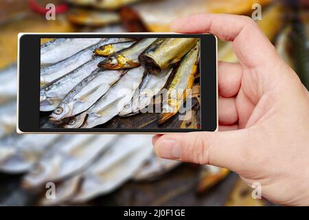 Pesce affumicato sullo schermo dello smartphone. Vendita di frutti di mare. Pesce nella finestra del negozio. Foto Stock