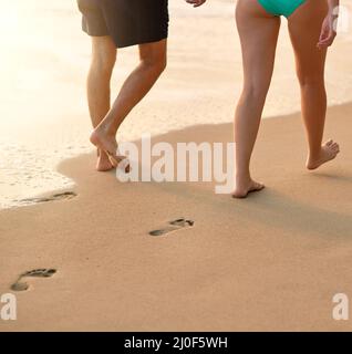 Fianco a fianco lungo il mare. Scatto corto di una coppia inidentificabile che cammina sulla spiaggia insieme. Foto Stock