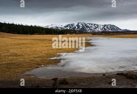 Paesaggio islandese con lago ghiacciato e montagne innevate in Islanda Foto Stock