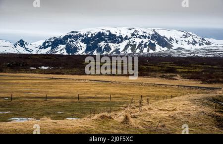 Paesaggio islandese con lago ghiacciato e montagne innevate in Islanda Foto Stock