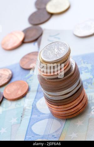 Monete in una pila e banconote in euro Foto Stock
