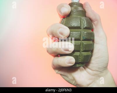 La mano tiene una vecchia granata sovietica su sfondo rosa. Foto di primo piano Foto Stock