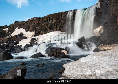 Acqua dalla cascata che spruzzi su un fiume roccioso Islanda Foto Stock