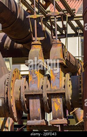 Ingranaggi e tubazioni arrugginiti e corrosi provenienti da macchinari abbandonati Foto Stock