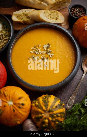 Zuppa di crema di zucca vegetariana fatta in casa servita in ciotola di ceramica. Decorato con semi Foto Stock