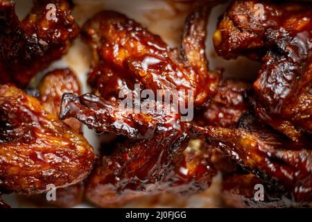 Primo piano sulle ali di pollo in salsa al barbecue. Servito su piatto di ghisa bianca Foto Stock