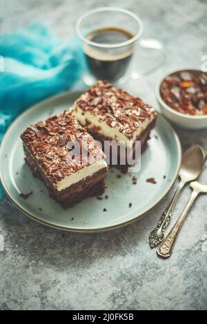 Deliziosa torta al cioccolato con strati serviti su piatto blu in ceramica. Con tazza di caffè nero fresco Foto Stock