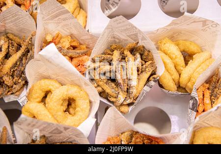 Confezioni di pesce fritto con calamari, odori e patate Foto Stock