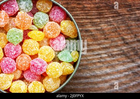 Colorati dolci succulenti multicolori Montpensier lolllipops in una scatola rotonda di stagno su sfondo di legno Foto Stock